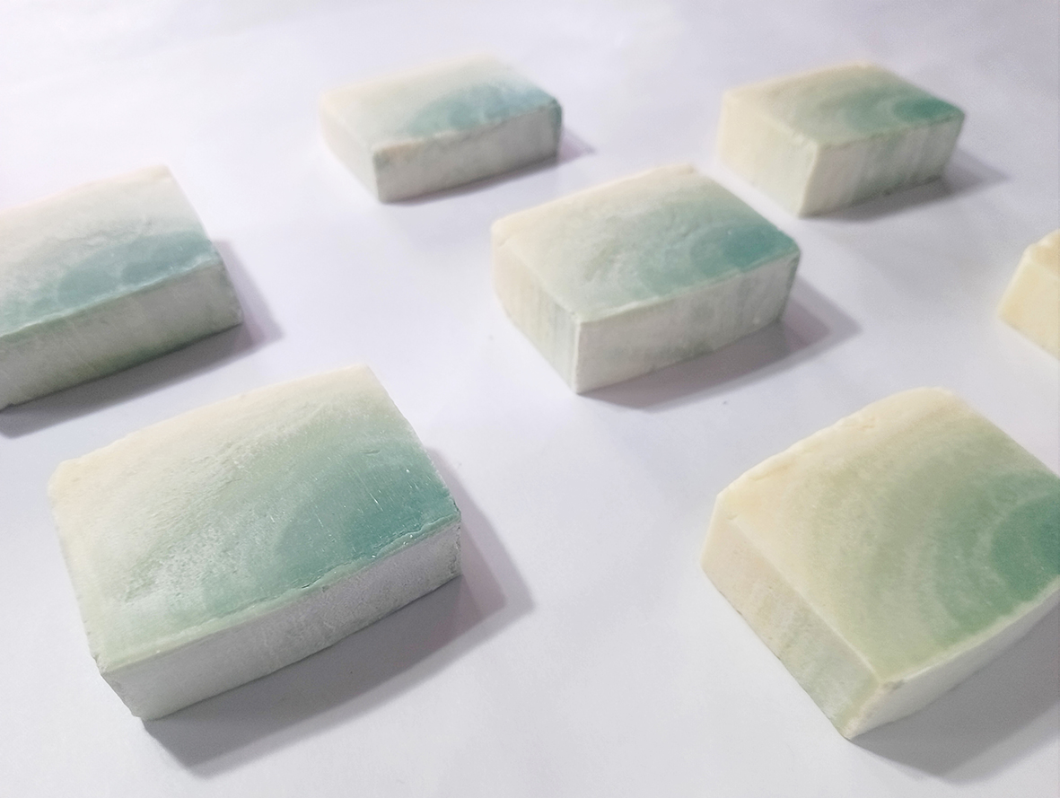 Green ombré soap in several pieces lying on a white background.